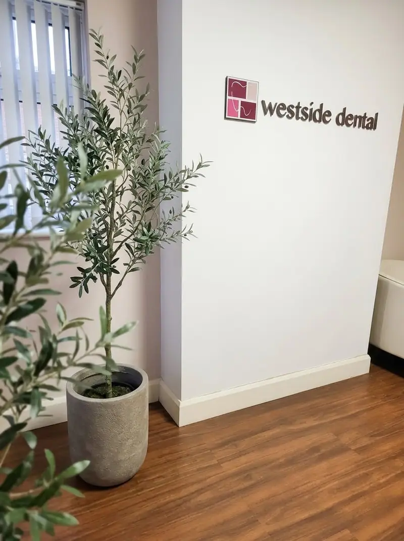 The Westside Dental sign in reception beside an olive tree
